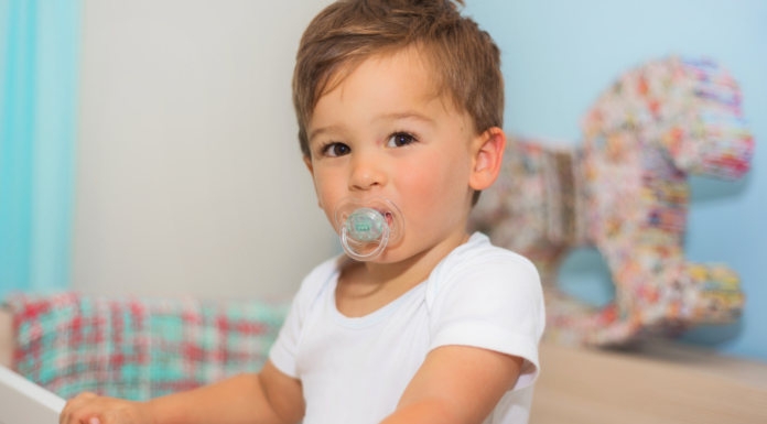 A boy with a pacifier in his mouth.