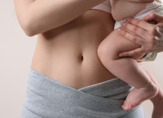 A mom holding her baby next to her postpartum body.