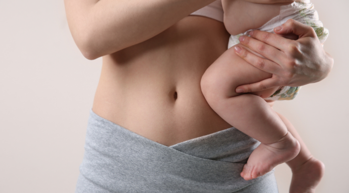 A mom holding her baby next to her postpartum body.