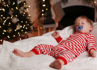 Should You Sleep Train During The Holidays? A toddler boy asleep in his Christmas pajamas.