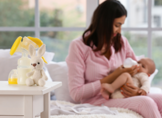 A woman breastfeeding her baby with pumping tools on the table.