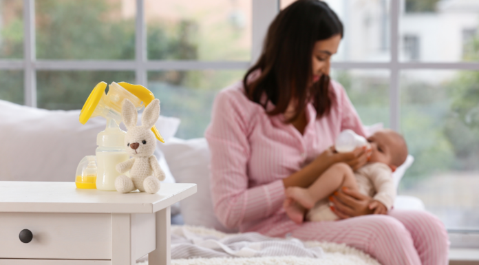 A woman breastfeeding her baby with pumping tools on the table.