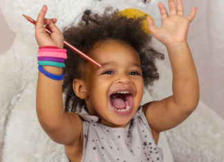A toddler happy raising her hands.