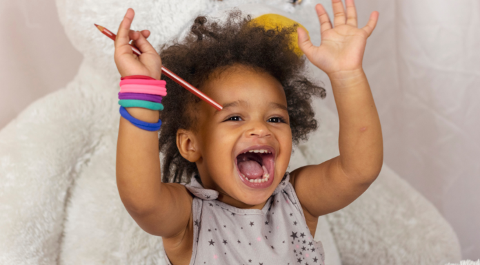 A toddler happy raising her hands.