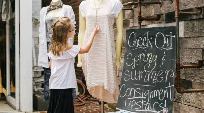 A girl looking at clothing at a spring consignment sale.