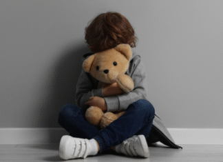 A scared child holding a teddy bear.