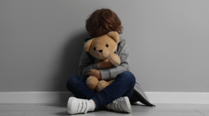 A scared child holding a teddy bear.