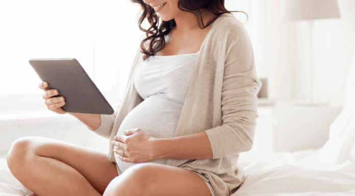 A pregnant woman looking at a calendar.
