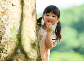 Don’t Be Shy: Raising an Introverted Girl An introverted girl hiding behind a tree.