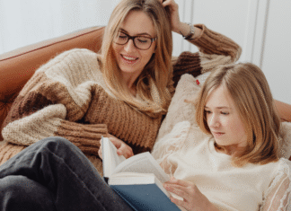 A mom and daughter reading a book on the couch.