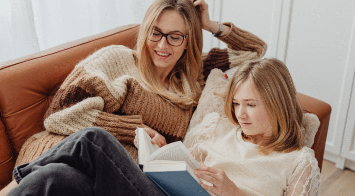 A mom and daughter reading a book on the couch.