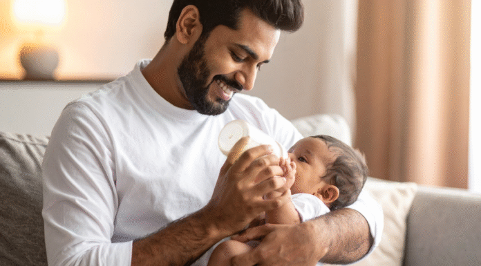 A dad feeding a baby a bottle.