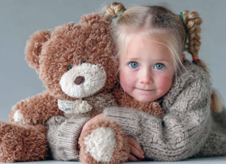 A little girl snuggling a Teddy bear.