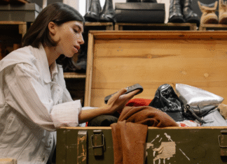 A woman looking through a chest of clothes for consignment.