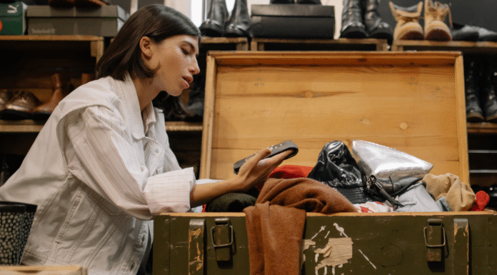 A woman looking through a chest of clothes for consignment.