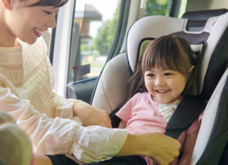 A mom getting her daughter out of a car seat.