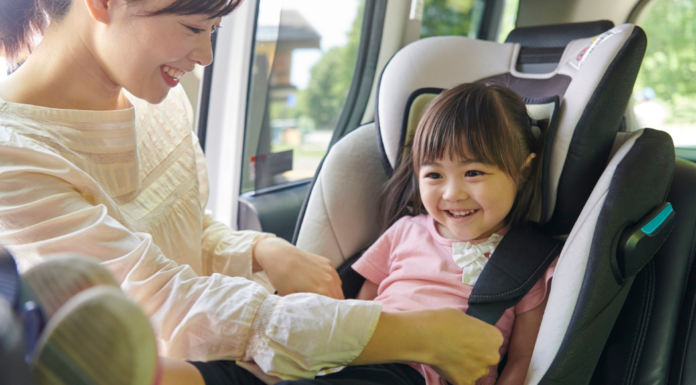 A mom getting her daughter out of a car seat.