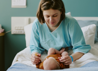 You’re Not Alone, Mama: Postpartum Support Services in Fairfield County A woman postpartum in the hospital with her baby.
