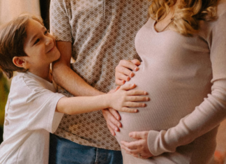 A boy touching his mom's pregnant belly.