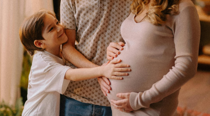 A boy touching his mom's pregnant belly.