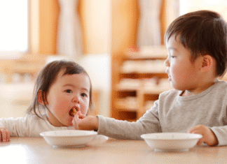 A brother feeding his younger sister.