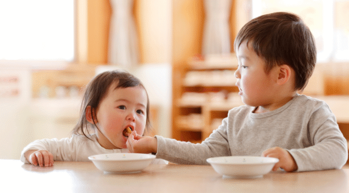 A brother feeding his younger sister.