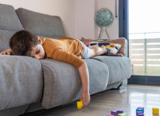 A boy laying on the couch bored.