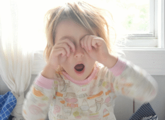A tired preschooler rubbing her eyes.