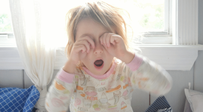 A tired preschooler rubbing her eyes.