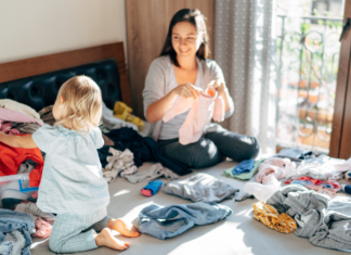 A woman folding laundry with her toddler.