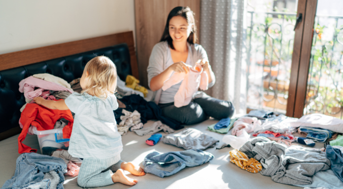 A woman folding laundry with her toddler.