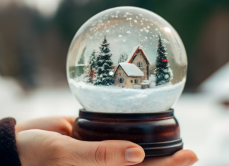 A hand holding a snow globe.