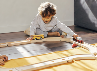 A boy playing with toy train tracks.