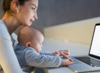 A mom holding her baby while she looks up information online.