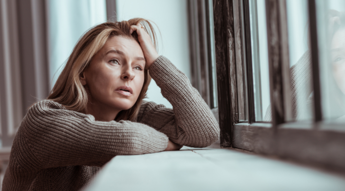 A sad woman looking out the window during winter.