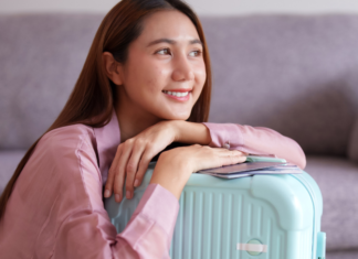 A woman smiling while holding her suitcase.
