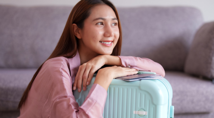A woman smiling while holding her suitcase.