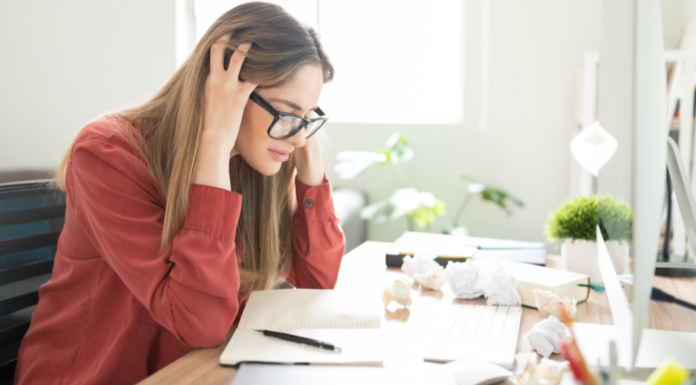A woman stressed at her desk looking at papers.