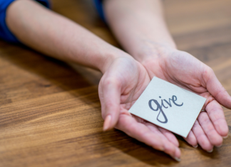A woman holding a note "give."