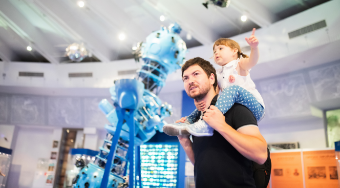 A man holding his child on his shoulders in a musuem.