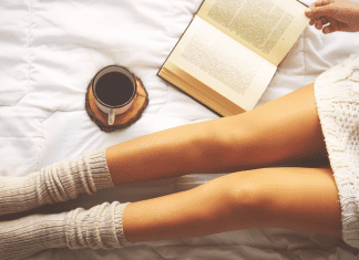 Womans legs in socks while reading a book and enjoying coffee.