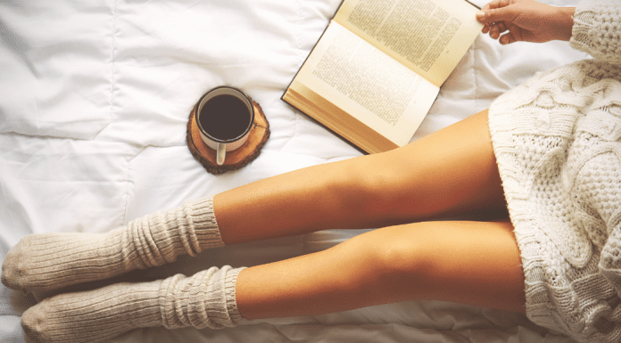 Womans legs in socks while reading a book and enjoying coffee.