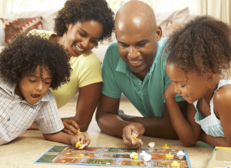 A family playing a board game laying on the floor.