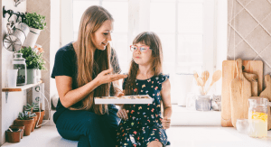 Mom holding a box of chocolates in front of a girl.