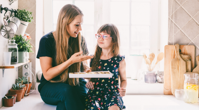 Mom holding a box of chocolates in front of a girl.
