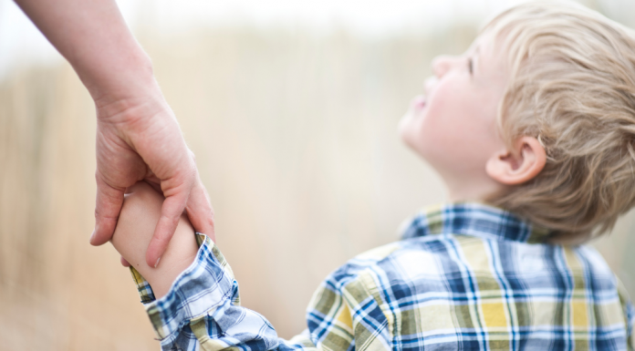 Holding hands with a little boy looking up.