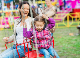 A mother and daughter on a swing ride at a fall festival.