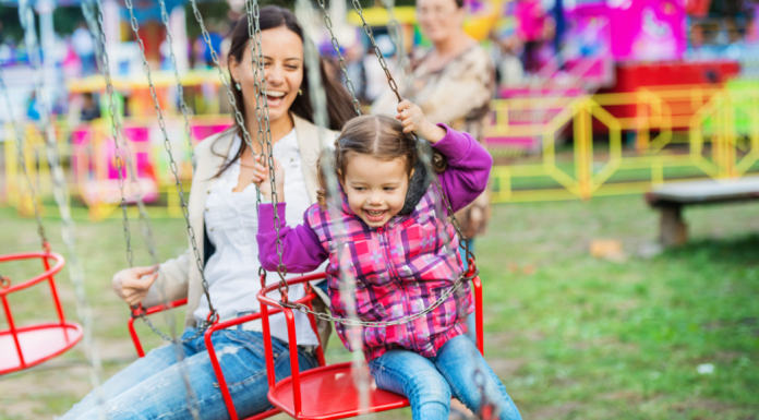 A mother and daughter on a swing ride at a fall festival.