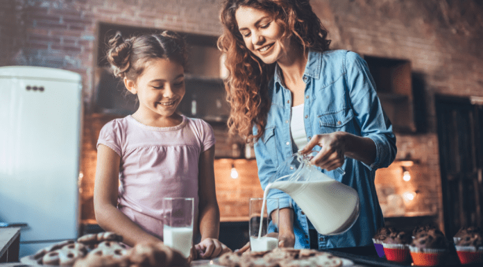 Mom pouring milk for her daughter.