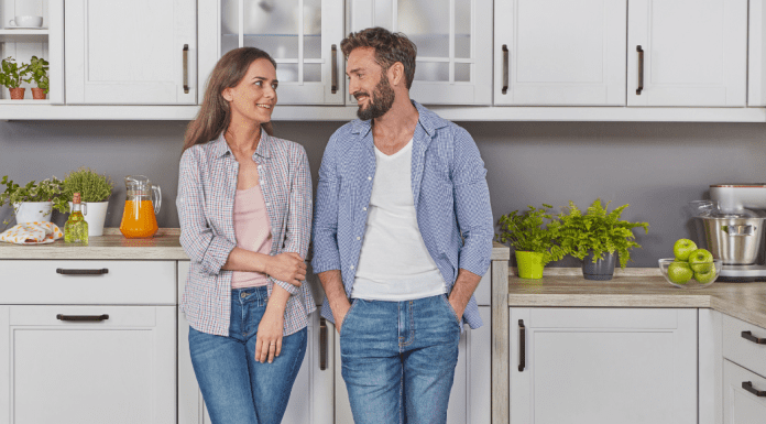 A woman and man standing next to each other in the kitchen.